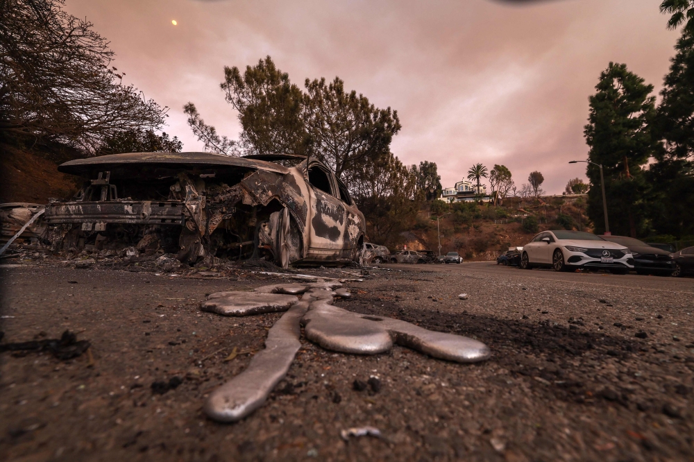 Molten metal flows from a car burnt-out by the Palisades Fire in the Pacific Palisades neighborhood of Los Angeles, California on January 10, 2025. (Photo by Valerie Macon / AFP)