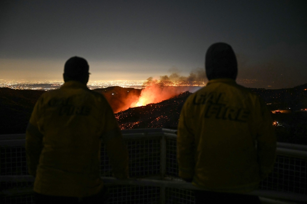 Firefighters monitor as the Palisades fire grows near the Mandeville Canyon neighborhood and Encino, California, on January 11, 2025. (Photo by Patrick T. Fallon / AFP)