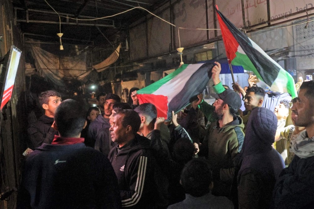 People celebrate along a street at Deir el-Balah in the central Gaza Strip on January 15, 2025, as news spread that a ceasefire and hostage release deal had been reached between Israel and Hamas. (Photo by Eyad Baba / AFP)