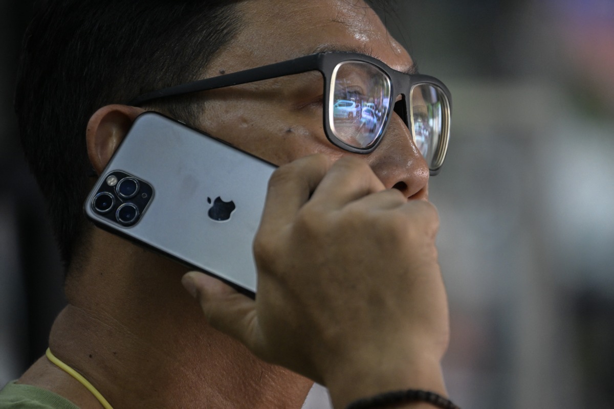 A man uses an Apple iPhone in Jakarta on January 8, 2025. (Photo by BAY ISMOYO / AFP)
