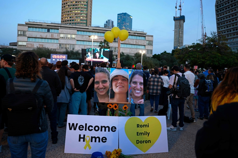 Supporters and relatives of Israeli detainees Romi Gonen, Emily Damari, and Doron Steinbrecher, watch a live television broadcast on their release on January 19, 2025.(Photo by Menahem Kahana / AFP)