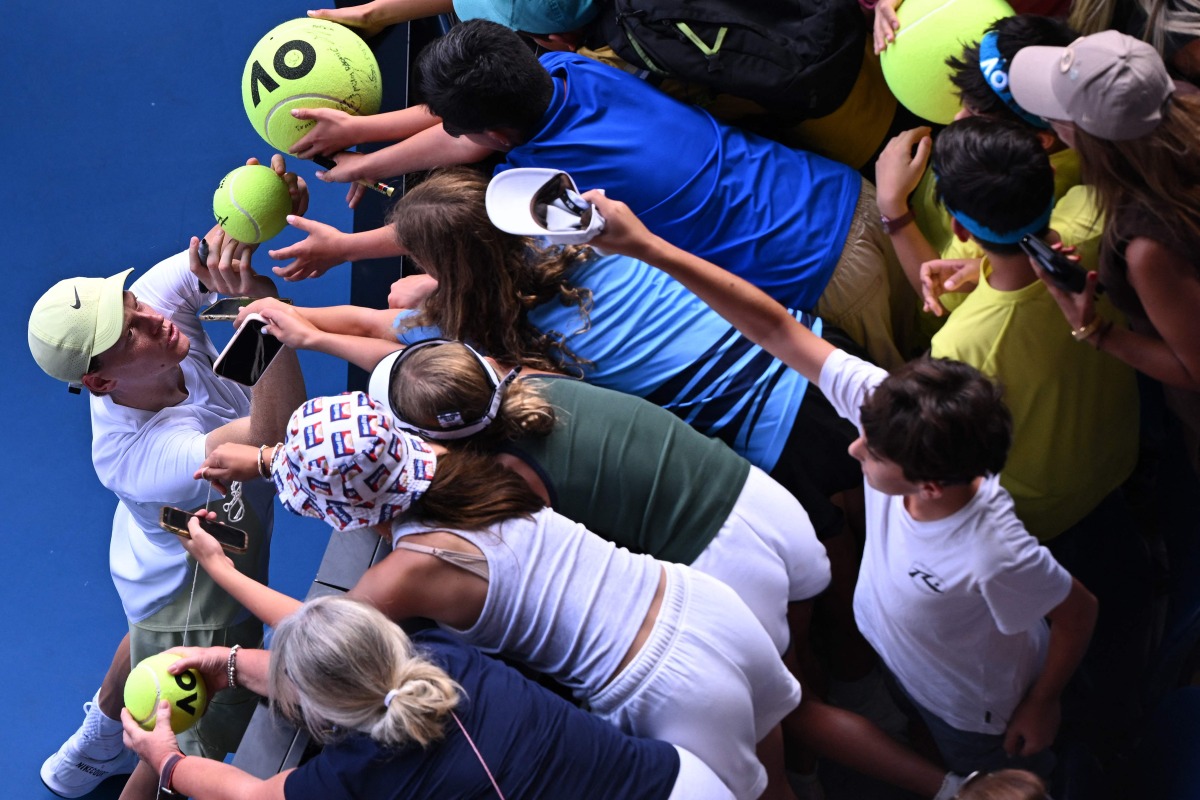 Italy’s Jannik Sinner signs autographs to fans following his victory over Denmark’s Holger Rune.