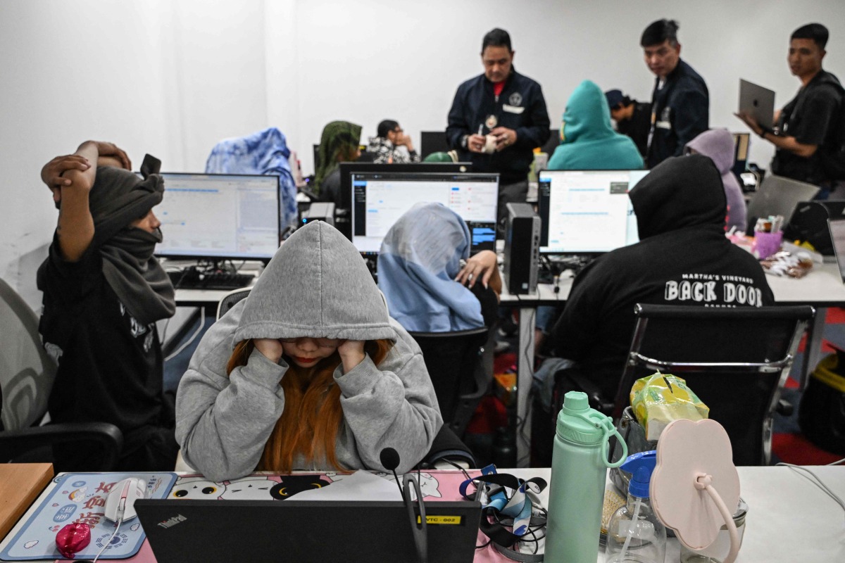 Workers sit at their desks during a raid by agents of the Presidential Anti-Organised Crime Commission (PAOCC) and the National Bureau of Investigation at an office of a suspected online scam farm in Manila on January 31, 2025. Photo by JAM STA ROSA / AFP