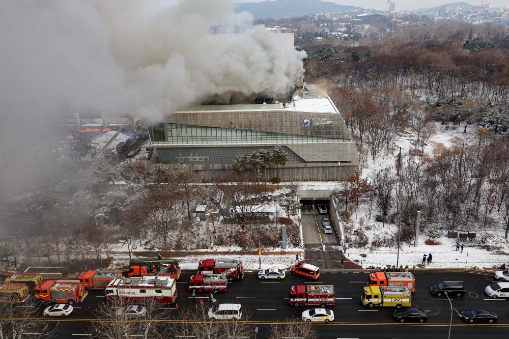 Fire engines are seen on a road as smoke rises from the roof of the National Hangeul Museum in Seoul on February 1, 2025. (Photo by YONHAP / AFP) 