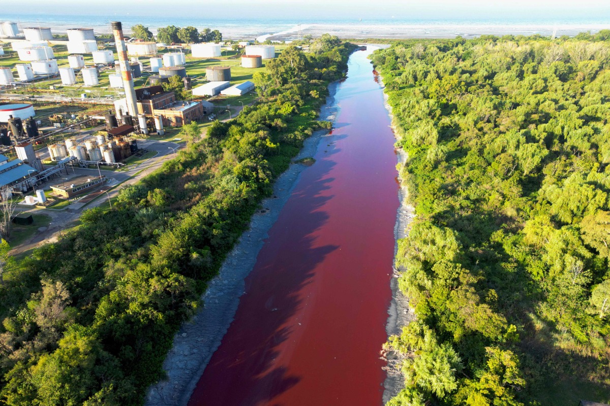 This aerial view shows an unusual reddish color of the Sarandi Canal seeping into the Rio de la Plata River in Sarandi, Avellaneda in the outskirts of Buenos Aires on February 6, 2025. (Photo by Juan MABROMATA / AFP)