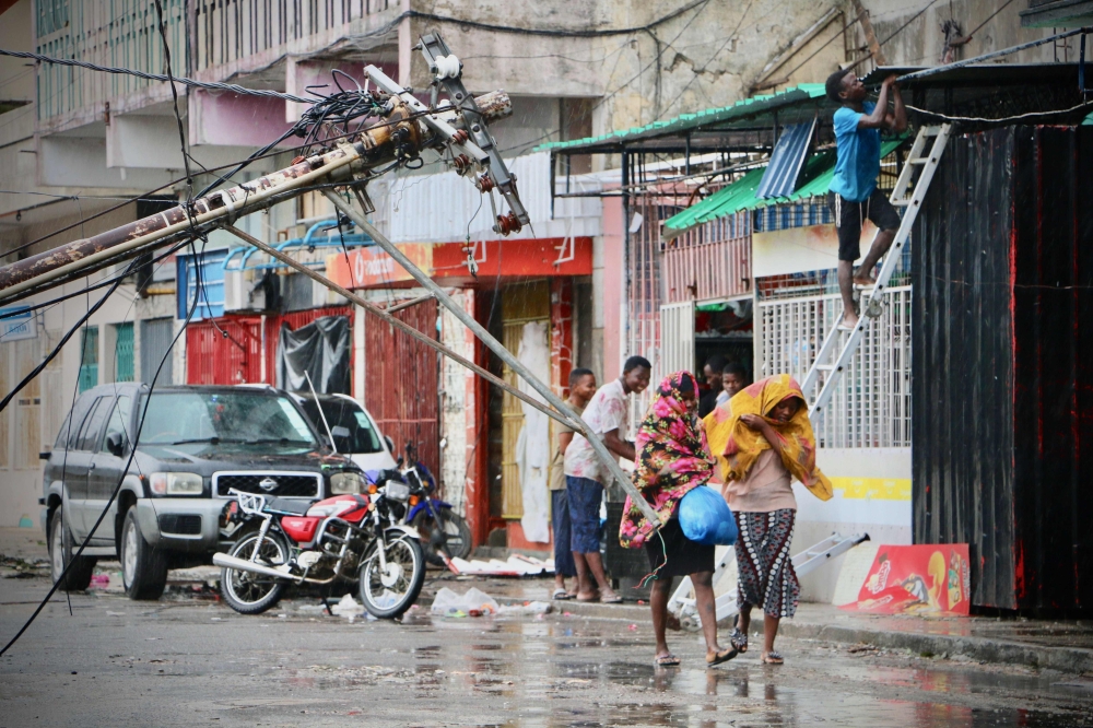 Residents are seen protecting themselves by the rain in the aftermath of the passage of the cyclone Idai in Beira, Mozambique, on March 17, 2019. AFP / ADRIEN BARBIER