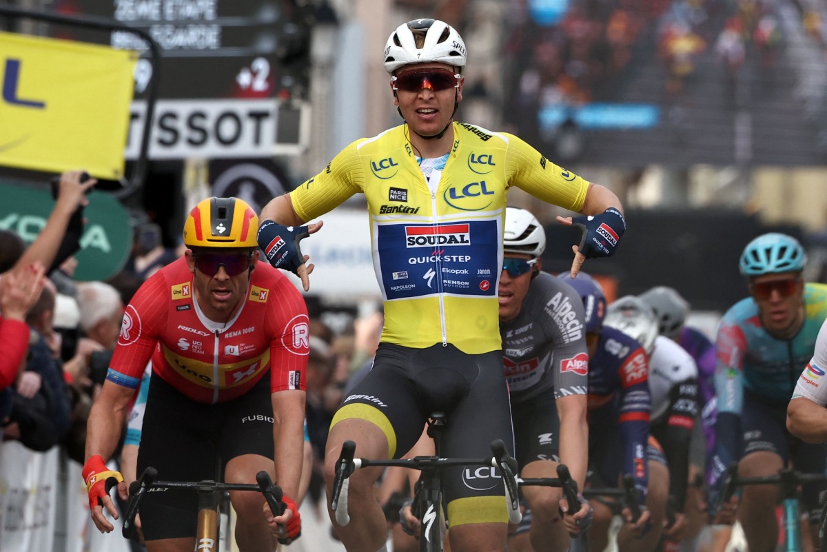 Soudal Quick-Step's Belgian rider Tim Merlier (C) wearing the overall leader's yellow jersey celebrates as he crosses the finish line to win the 2nd stage of the Paris-Nice cycling race, 183,9 km between Montesson and Bellegarde, on March 10, 2025. (Photo by Anne-Christine POUJOULAT / AFP)
