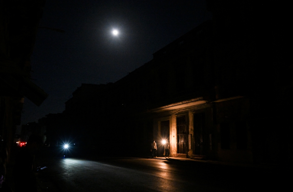 Cubans chat on the entrance of a house during a general blackout in Havana on March 14, 2025. (Photo by Yamil Lage / AFP)