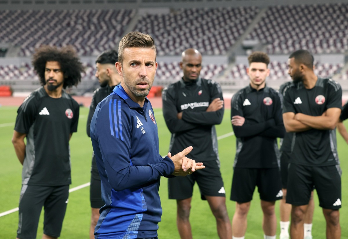 Qatar head coach Luis Garcia speaks to players during a training session.