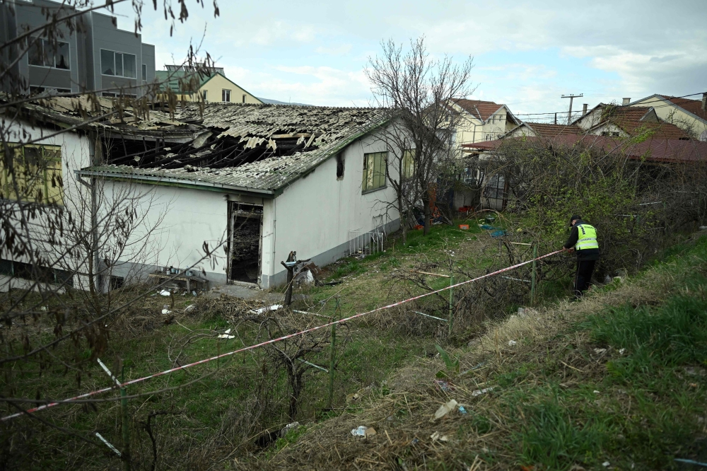 Police officers establish a perimeter with caution tape around a nightclub where a deadly fire broke out a day prior, in Kocani on March 17, 2025. (Photo by Robert ATANASOVSKI / AFP)