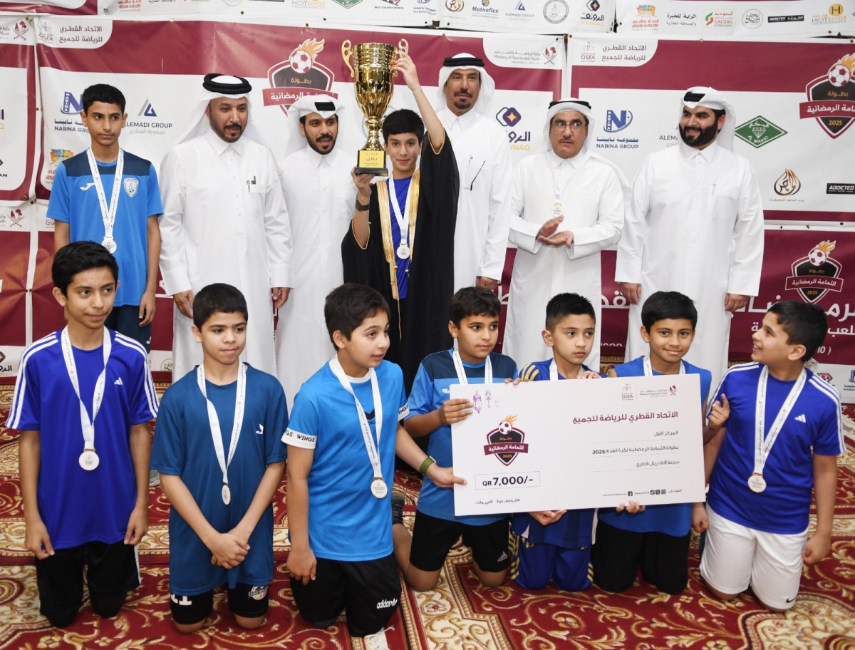 Al Adaam players pose with officials as their captain lifts the trophy. 