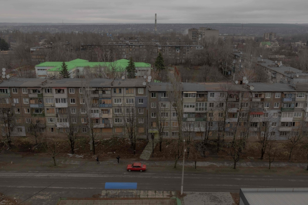 A car drives past residential buildings damaged by air attacks, in Kostyantynivka, eastern Donetsk region, on March 17, 2025, amid the Russian invasion of Ukraine. (Photo by Roman Pilipey / AFP)