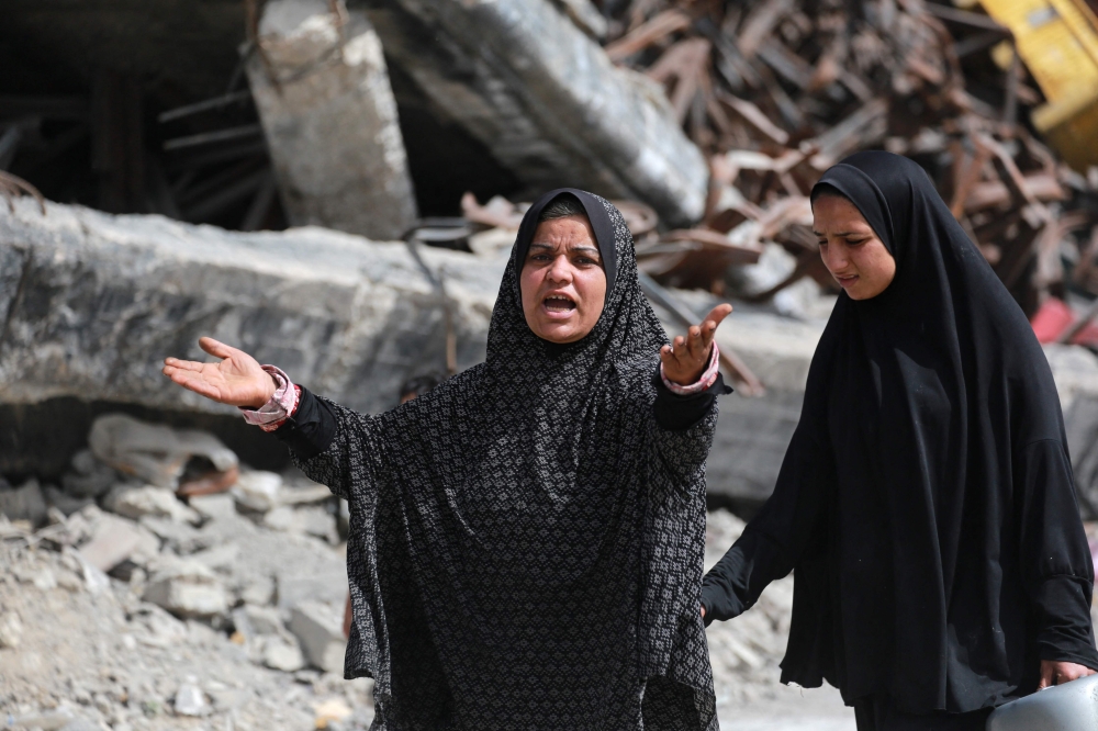 A woman gestures as Palestinians leave Beit Hanun in the northern Gaza Strip with their belongings, heading towards Gaza City following Israeli evacuation orders on March 19, 2025. (Photo by Bashar Taleb / AFP)