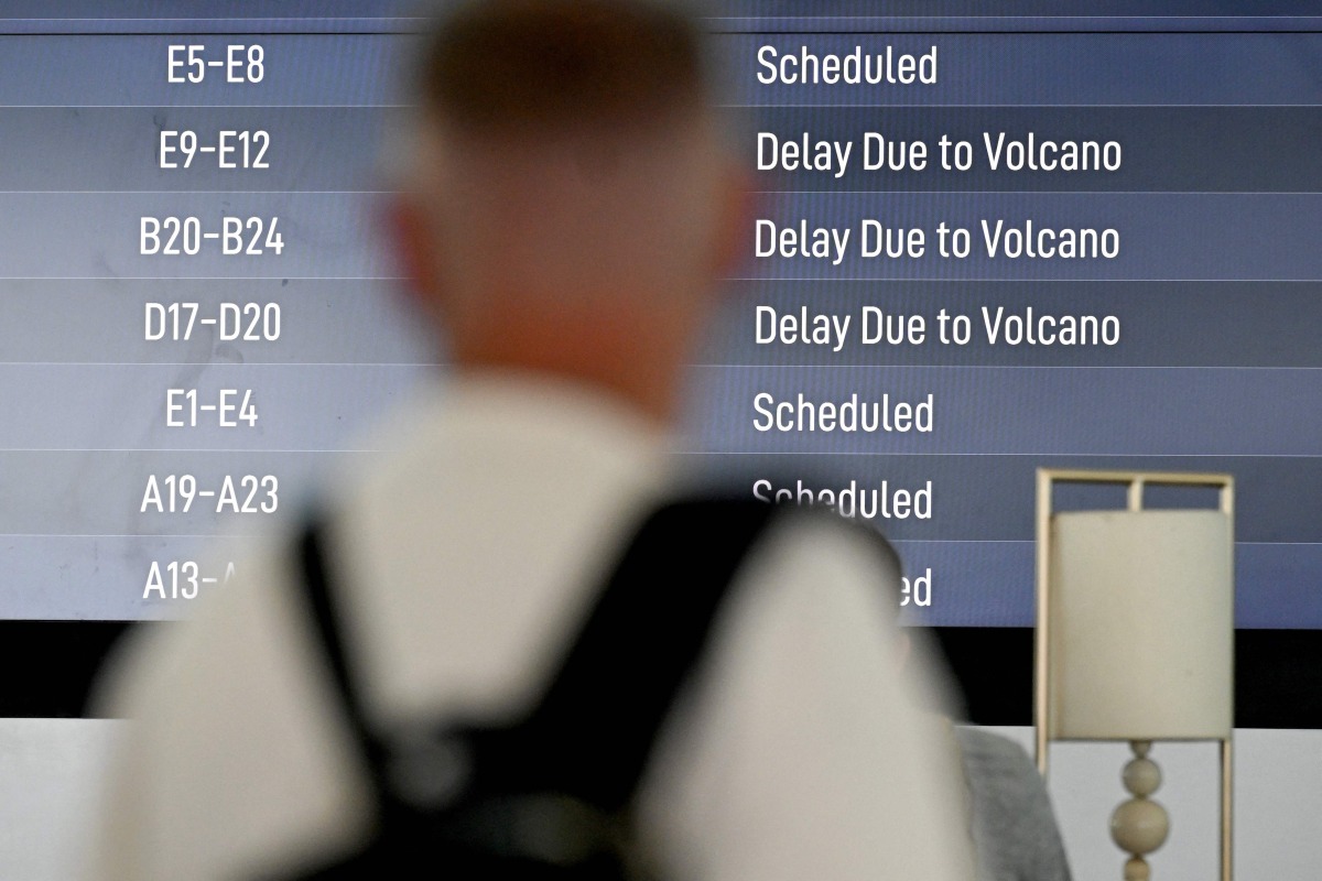 Passengers look at an electronic board displaying cancelled flights at the Ngurah Rai International Airport in Tuban near Denpasar on Indonesia's resort island of Bali on March 21, 2025, after Mount Lewotobi Laki-Laki volcano in the archipelago nation's east erupted, shooting dark ash eight kilometres into the sky. (Photo by SONNY TUMBELAKA / AFP)