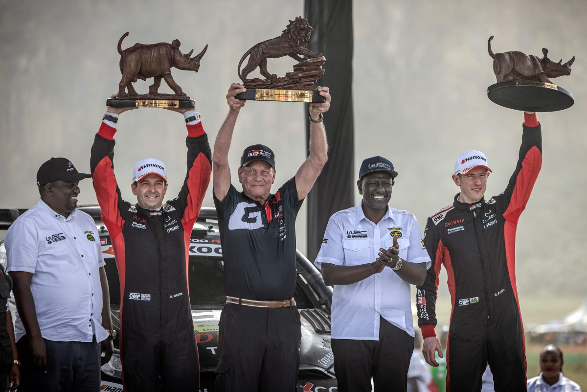 Toyota Gazoo Racing WRT's British driver Elfyn Evans (R) and co-driver Scott Martin (2nd L) hold their trophies as they pose for the media with President of Kenya William Ruto (2nd R) after winning the World Rally Championship (WRC) Safari Rally Kenya in Naivasha on March 23, 2025. (Photo by Luis TATO / AFP)
