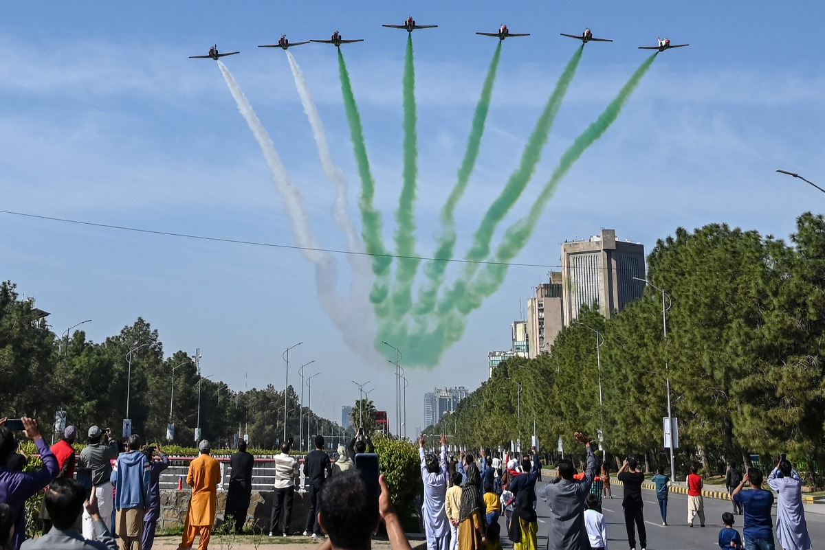 People watch as the Pakistan Air Force Karakoram-8 (K-8) aircraft team performs aerobatic manoeuvres during the national day parade as they fly past near the President's House in Islamabad on March 23, 2025. (Photo by Aamir QURESHI / AFP)
