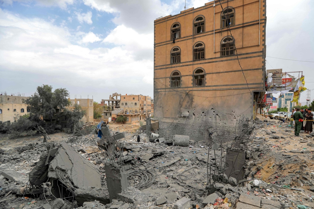 People gather by the rubble of a collapsed building at the site of a reported US air strike on Yemen's capital Sanaa on March 24, 2025. (Photo by Mohammed Huwais / AFP)
