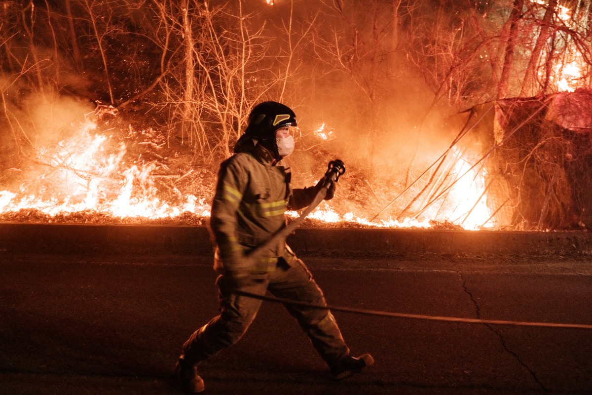 A firefighter prepares to spray water as wildfires spread along the slopes in Uiseong, South Korea, on March 24, 2025. Photo by YASUYOSHI CHIBA / AFP.