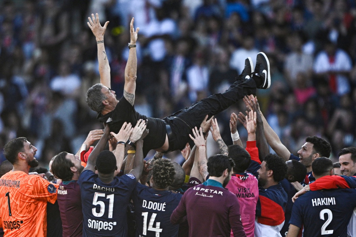 Paris-Saint Germain's players throw up in the air Paris Saint-Germain's Spanish headcoach Luis Enrique as they celebrate after winning the match and the French championship title after the French L1 football match between Paris Saint-Germain (PSG) and SCO Angers at The Parc des Princes Stadium in Paris on April 5, 2025. (Photo by JULIEN DE ROSA / AFP)
