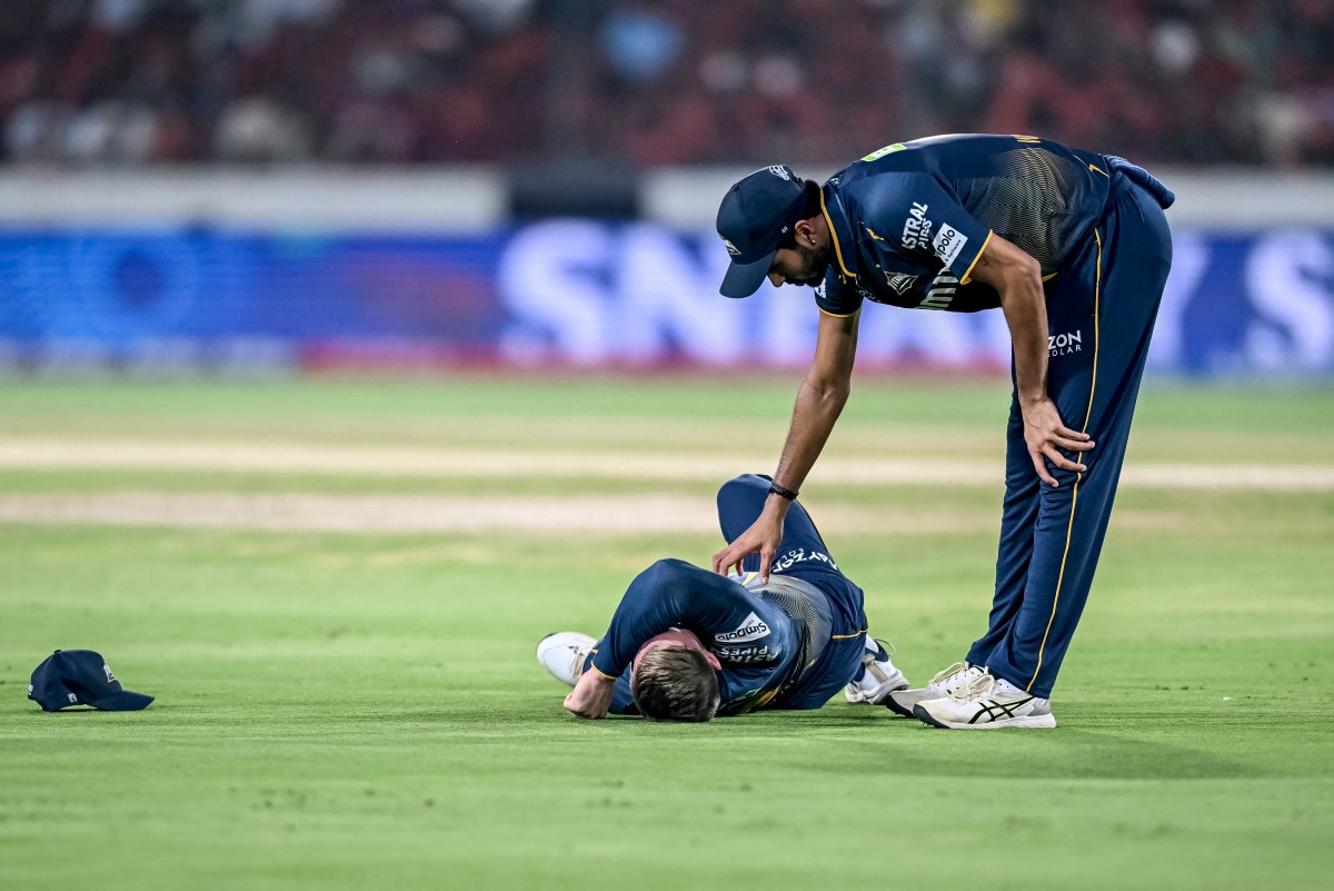 Gujarat Titans' Washington Sundar (R) checks on his teammate Glenn Phillips during the Indian Premier League (IPL) Twenty20 cricket match in Hyderabad on April 6, 2025. (Photo by Noah Seelam / AFP) 