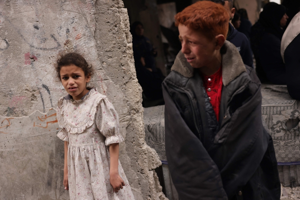 Palestinian children cry as rescuers search the rubble after an Israeli strike on the Manoun family home in Jabalia in the northern Gaza Strip on April 13, 2025. (Photo by Bashar Taleb / AFP)
